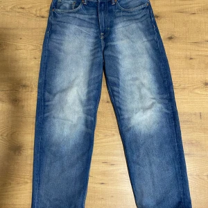 Blå loose fit jeans från H&M - Säljer ett par blå loose fit jeans från H&M i klassisk denim med snygg tvätt och raka ben. Jeansen har fem fickor och normal midja, perfekt för en avslappnad stil. Storlek 31/32.