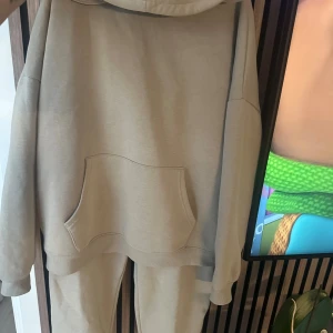 Beige hoodie från FB Sister i bomull - Säljer en beige hoodie från FB Sister i storlek M. Tröjan har huva, magficka och är tillverkad i mjuk bomulls- och polyestermix. Perfekt för chill dagar och har en relaxed passform med långa ärmar och ribbade muddar.