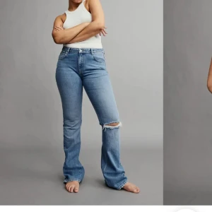 Blå bootcut jeans med slitning - Snygga ljusblå jeans med bootcut-modell, mid midja och är tillverkade i jeansmaterial. 