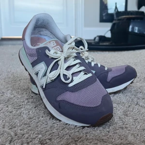 Lila New Balance 500 sneakers - Säljer mammas New Balance 500 sneakers i snygg lila och lavendelfärg med vita detaljer och logga. Skorna har mesh och mocka på ovandelen, vita snören och en klassisk retrostil. Perfekta för dig som gillar streetwear och vill ha bekväma sneakers med cool vibe. Säljer dessa snygga skorna för dem börjar bli får små! Är så gott som nyskick❣️
