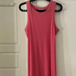 Rosa ribbad långklänning Kappahl - Säljer en snygg rosa långklänning från Kappahl i storlek S. Klänningen är ärmlös och har en ribbad struktur som ger en cool och modern vibe. Rund halsringning och mjukt bomullsmaterial gör den superbekväm att bära hela dagen.