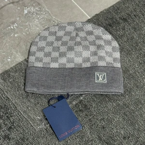 Grå stickad mössa med monogrammönster - Mysig grå mössa i stickad modell med klassiskt monogrammönster. Köpt för flera år sedan och använd sparsamt. I fint skick utan defekter. Tyvärr finns inget kvitto kvar eftersom den är äldre. Kan skicka fler bilder på detaljer vid intresse.