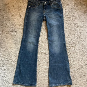 Lågmidjade blå bootcut jeans från H&M  - Snygga blå bootcut jeans från H&M Divided i storlek 38. Klassisk femficksmodell med normal passform och lätt tvättad look. Jeansen har låg midja och är tillverkade i jeansmaterial med lite stretch för extra komfort.