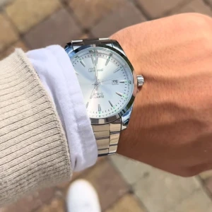 Silverfärgad klocka från Doventi - Stilren klocka från Doventi med rund urtavla i silver och datumvisning. Klockan har en klassisk länk i metall och minimalistisk design med tydliga markeringar. Perfekt accessoar för dig som gillar en clean och modern look.