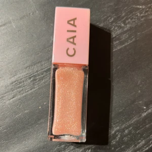 CAIA glittrigt läppglans rosa Pinky gloss - Superfint läppglans från CAIA i en ljusrosa nyans med massor av skimmer. Kommer i en snygg fyrkantig förpackning med rosa lock och guldig logga. Perfekt för att ge läpparna en glossy och glittrig finish.