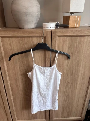 Vitt linne - Säljer en enkel och stilren vit linnetopp från H&M i storlek 170. Toppen har tunna axelband!