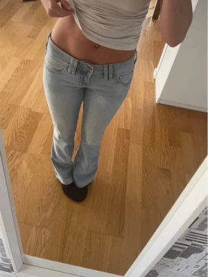 Hollister Low-Rise Bootcut Jeans – W26 | Y2K Trend - Trendiga low-rise bootcut jeans från Hollister – sitter sjukt snyggt, redo att skickas direkt 💙 Klassisk bootcut-passform som sitter tajt över höfter och lår och faller snyggt över skorna.  🔹 Midja: Low rise 🔹 Modell: Bootcut 🔹 Storlek: W26 / Regular 🔹 Färg: Ljusblå denim 🔹 Märke: Hollister 🔹 Originalknappar med Hollister-logga Mycket bra skick, använda fåtal gånger – se bilder för detaljer.  Mått: Midja-36cm Innerben-76,5cm Ytterben-98cm Lår-23cm