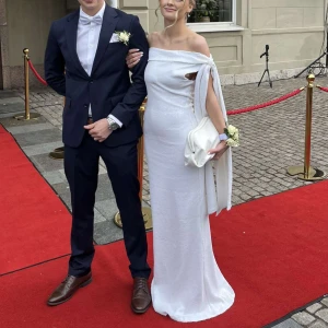 Vit glittrig bal långklänning med offshoulder - Säljer en elegant vit långklänning med paljetter. Klänningen har en figurnära passform och en snygg draperad axel med lång tygdetalj. Perfekt för bal eller festliga tillfällen. 🫶🏼använd 1 gång på min bal 2025, kan lossnat någon paljett men ingen jag lägger märke till när jag kollar på klänningen. Smutsigt längst ner på klänningen på insidan och lite slitet längst ner (kom privat för bilder om du är intresserad). Jag är 162 och hade 7cm klackar och den va fof för lång. 🩷