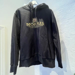 Morris Hoodie - En svart morris hoodie med stort tryck på framsidan. Den är storlek S men kan även massa lite större. 