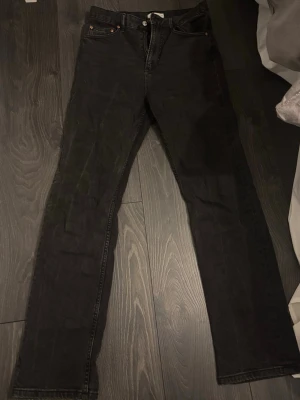 Svarta jeans från Gina Tricot - Säljer ett par svarta jeans från Gina Tricot i modellen Perfect Jeans, storlek 36. Jeansen har klassisk femficksdesign, raka ben och normal passform. Materialet är jeans med snygg svart tvätt och silverfärgad knapp framtill. Perfekt till din jeanssamling!