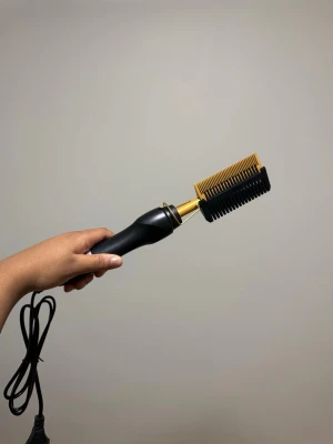 Hot Comb (värmekam) - Säljer en elektrisk värmekam med svart handtag och guldfärgad metallkam. Perfekt för att styla och räta ut håret. Kamdelen är i metall och handtaget i plast, med sladd för eluttag. Enkel att använda för att få till släta och glansiga hårslingor. Värmekamen har 3 olika dradtemperaturer: 160,180 och 200. Den kommer även med en svart skållningsskydd som visas i bilderna. 