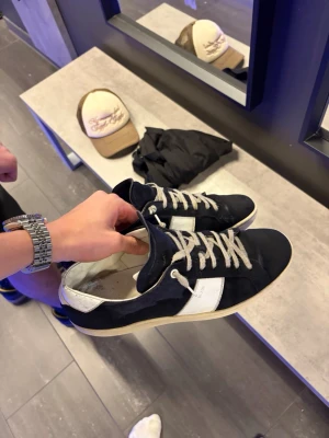 Mörkblåa Saint Laurent SL/02 - Säljer ett par mörkblåa Saint Laurent SL/02 sneakers med vit kontrastdetalj på sidan och vit häl. Skorna har snörning och är tillverkade i mocka. Skorna är sjukt eftertraktade och säljs inte längre av Yves Saint Laurent. Vad jag har hört är nypriset över 9000kr. Skorna har precis blivit tvättade av en mockaspray, därför är de lite blöta! Bara att höra av dig vid minsta fundering😇