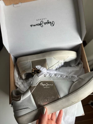 Vita och guldiga sneakers från Pepe Jeans - Snygga sneakers från Pepe Jeans i vitt och guld med leopardmönstrad detalj på plösen. I princip helt nya 🤩 