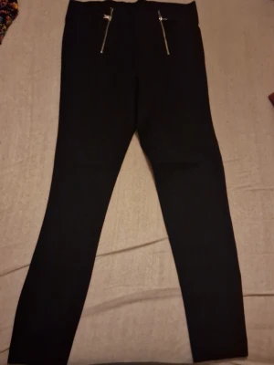 Svarta byxor Zara Trafaluc L - Svarta byxor från Zara Trafaluc Collection i storlek L. Byxorna har slim fit, hög midja och två snygga dragkedjor framtill som detalj. Materialet känns mjukt och stretchigt, perfekt för en clean och stilren look. Nästan helt oanvänd. Priset kan diskuteras🫶