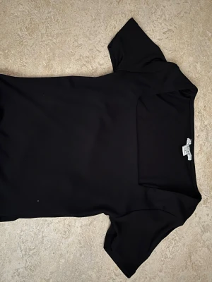 Svart topp från Amisu/New yorker med kort ärm - En svart topp från Amisu med korta ärmar och rund halsringning. Enkel och clean design som passar till det mesta. Tillverkad i ett mjukt och stretchigt material för skön passform.