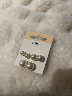 Pärlörhängen i set från Glitter - Säljer ett set med tre par klassiska pärlörhängen från Glitter i olika storlekar. Örhängena är vita och har en rund form med metallstift. Perfekta för att mixa och matcha till olika looks.