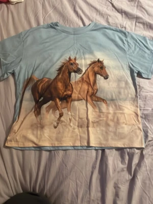 Ljus blå tröja med hästar - Aldrig använd. Jätte fin färg.