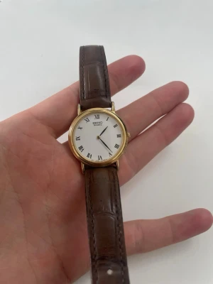 Vintage seiko damklocka - En riktigt fräsch seiko från 80-talet i perfekt skick. Med romerska siffror i urtavlan och alligatorskinn på bandet.             Anledningen till det fina priset är för att klockan behöver ett batteribyte.                                     Vid minsta fråga är det bara skicka ett meddelande!