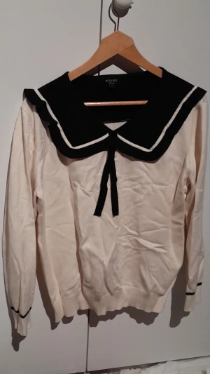 Beige tröja - En beige långärmad tröja med svart krage.