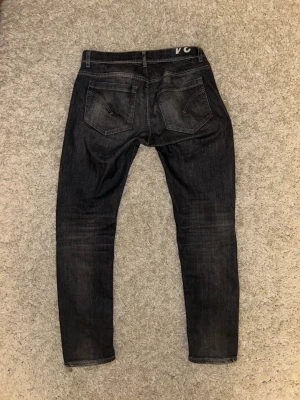 Svarta slim fit jeans från Dondup  - Snygga svarta slim fit jeans från dondup med klassisk design och diskreta slitningar. Jeansen har en mörk tvätt och raka ben, perfekta för en stilren look. 