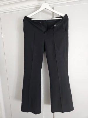 Kostymbyxor  - Svarta kostymbyxor från gina tricot i storlek M. Högmidjade bootcut. Liten reva på baksidan av benet (se sista bilden).