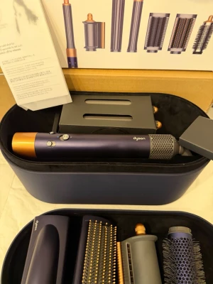 Dyson Airwrap Complete Long hårstyler - Säljer en Dyson Airwrap Complete Long i mörkblå och kopparfärg. Setet innehåller flera stylingtillbehör som borstar och locktillbehör, allt i en snygg förvaringsbox. Perfekt för att skapa olika frisyrer med minimal värme.