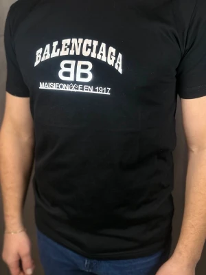 Svart  t-shirt med tryck - Snygg svart t-shirt  med vit logga och text på bröstet. Klassisk passform och rund halsringning. Perfekt för dig som gillar streetwear och vill ha en stilren look med exklusiv känsla.