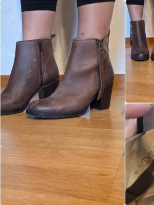 Bruna stövletter från Sixtyseven - Snygga bruna stövletter från Sixtyseven med grov klack och dragkedja på sidan. Tillverkade i läder med rundad tå och stilren design. Perfekta för dig som vill ha en klassisk men trendig look. Aldrig använda utomhus, färgen ska ha en "sliten" look.