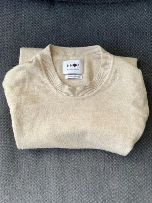 NN07 stickad tröja beige - Snygg stickad tröja från NN07 (No Nationality) i merinoull. Tröjan är inköpt för ett år sedan (nypris 1500kr) och är i mycket gott skick. 