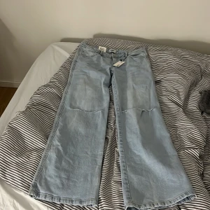 Ljusblåa vida jeans från Lager 157 - Säljer ett par ljusblåa jeans från Lager 157 med breda ben och hög midja. Jeansen har klassisk femficksdesign och är gjorda i mjukt denimtyg. Perfekta för en avslappnad och trendig look.