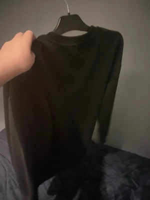 Svart sweatshirt från The North Face - Säljer en svart sweatshirt från The North Face med broderad logga på bröstet. Tröjan har rund halsringning och långa ärmar. Perfekt för dig som gillar enkel och stilren streetwear.