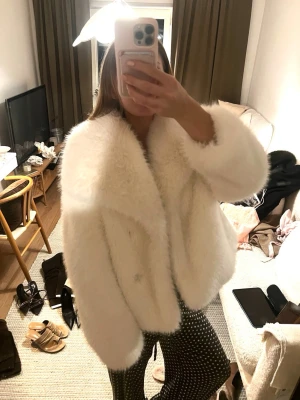 Vit fluffig fuskpälsjacka ZARA - Säljer en supermjuk och fluffig vit fuskpälsjacka med bred krage och avslappnad passform. Jackan har långa ärmar och ger en lyxig känsla till din outfit. 