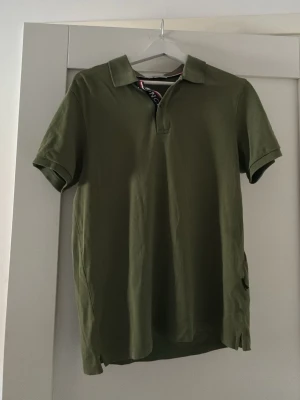 Olivgrön Moncler pikétröja - Snygg olivgrön pikétröja från Moncler med klassisk krage och korta ärmar. Tillverkad i bomull för en bekväm känsla. Perfekt för en avslappnad men stilren look.