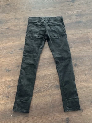 Svarta replays - 33/32 Säljer ett par svarta skinny jeans från Replay med klassisk femficksdesign och låg midja. Jeansen har smal passform och är tillverkade i stretchigt material för extra komfort. Perfekta för en stilren och enkel look.