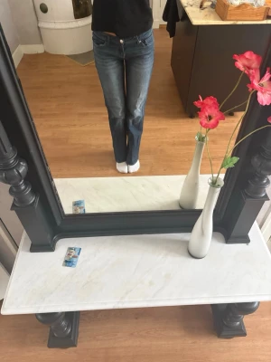 Blå bootcut jeans med låg midja - Säljer ett par klassiska blå vida jeans med låg midja. Jeansen har en snygg tvätt med lätt slitning och raka ben som går ut lite nedtill.