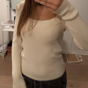 Ribbad beige långärmad tröja S-M - Säljer en ribbad beige långärmad tröja med fyrkantig ringning. Tröjan har en slim passform och är tillverkad i ett mjukt, stretchigt material som sitter snyggt på kroppen. Jätte snyg me ett par svarta jeans. 