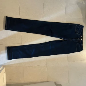 Levi's skinny jeans midwaist blå - Mörkblå skinny jeans från Levi's med klassiska bakfickor och kontrastsömmar. Modellen är mid rise och har en smal passform hela vägen ner. Tillverkade i stretchigt denim för extra komfort. Perfekta för dig som gillar en clean och tidlös look.