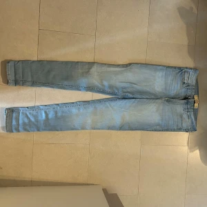Hollister ljusblå super skinny jeans - Säljer ett par ljusblå Hollister Super Skinny jeans med hög midja. Jeansen har klassiska fem fickor, snygga dekorsömmar på bakfickorna och en smal passform hela vägen ner. Perfekt för dig som gillar en tajt och modern look.