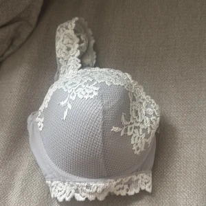 Intimissimi Bh  - Supersnygg grå Bh med vit spets och blommigt mönster. Den har vadderade kupor och fina spetsdetaljer längs kanterna. 