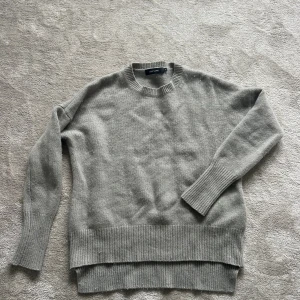 Grå kashmirtröja från Lisa Yang - Supermjuk grå stickad tröja från Lisa Yang i lyxig kashmir. Tröjan har rund hals, långa ärmar och breda ribbade muddar vid ärmslut och nederkant. Perfekt oversized passform för en chill och stilren look. Nypris 4495kr