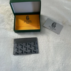 Svart kortfodral  - Stilrent svart kortfodral med ikoniskt grafiskt mönster i vitt och grått. Tillverkat i skinn och canvas, perfekt för kort och ID. Kommer med originalask och dustbag. En klassisk accessoar med lyxig känsla.