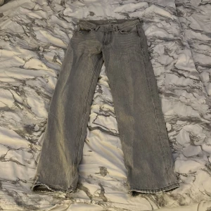 Grå jeans från Gina perfect jeans, stl 34 - Säljer ett par grå jeans från gina perfect jeans i storlek 34. Jeansen har raka ben och går ut på slutet, klassisk femficksdesign och råa, fransiga benslut för en avslappnad vibe. Perfekta för dig som gillar en enkel men snygg look. 