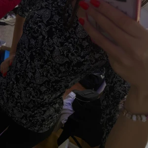 Svart blommig långärmad topp - Svart långärmad topp med vitt blommigt mönster över hela plagget. Snygg och figurnära passform, perfekt för dig som gillar detaljerade prints. Materialet känns mjukt och stretchigt, vilket gör den bekväm att bära hela dagen.