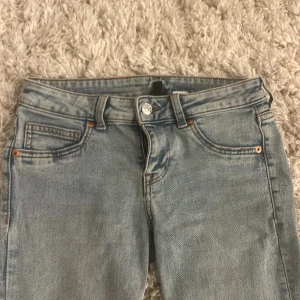 Ljusblå bootcut jeans - Säljer ett par ljusblå jeans med klassisk femficksdesign och bootcut-ben. Jeansen har låg midja och är tillverkade i denim med snygg tvättad look. Perfekta för dig som gillar en avslappnad men trendig stil.