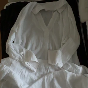 Vit långärmad skjort klänning - Säljer en vit skjort klänning med långa ärmar. Klänningen har v-ringning och breda manschetter. 