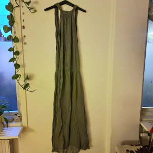 Grön långklänning - Grön långklänning. Djup urringning i ryggen, knytning i halsen och indragning mid höften/midjan. Passar en lång person mycket bra skulle jag tro. Lite Sheer i tyget, då det är så tunt (kan vara bra att veta). Fler bilder kommer
