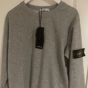 Grå sweatshirt från Stone Island - säljer en tvärfet stone island tröja till ett ännu skönare pris, alla orginal lappar är kvar och allt sitter som det ska, anledningen till att jag vill sälja den är att jag vill byta stil