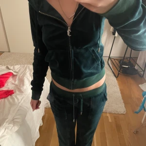 Mörkgrönt juicy couture set - Mörkgröt juicy set! Jättemysigt till hösten! Byxorna har en liten defekt framtill från förra ägaren. Dock syns den knappt när man har på sig dom. Fläcken går inte bort i tvätten då ja testat att tvätta, men som sagt syns det knappast och jag har knappt märkt av den.