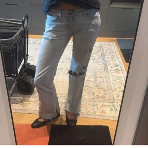 Ljusblå jeans med hål - Säljer ett par fina ljusblå jeans från wrangler med hål och är lågmidjade. Midjemåttet är ca 38cm och innerben är 78cm  