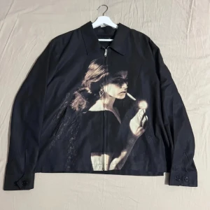 Undercover Cindy Sherman Jacka - Svart jacka från Undercover med stor grafisk print framtill. Jackan har dragkedja både framtill och i sidorna, klassisk krage och långa ärmar med knappdetaljer. Utan debatt, det finaste plagget jag har haft.